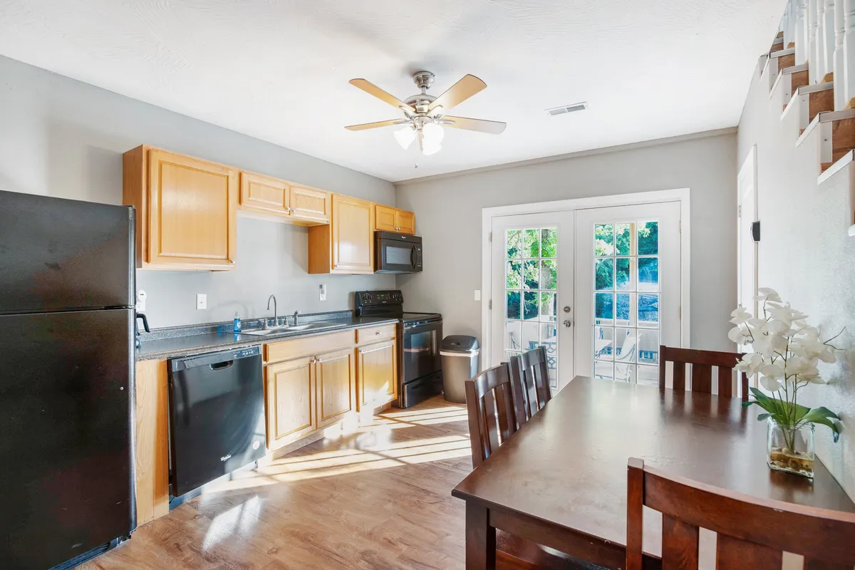 A view of the kitchen and dining area with appliances, dining table, and French doors that lead out to the deck. The space feels warm and designed for both everyday meals and special gatherings.