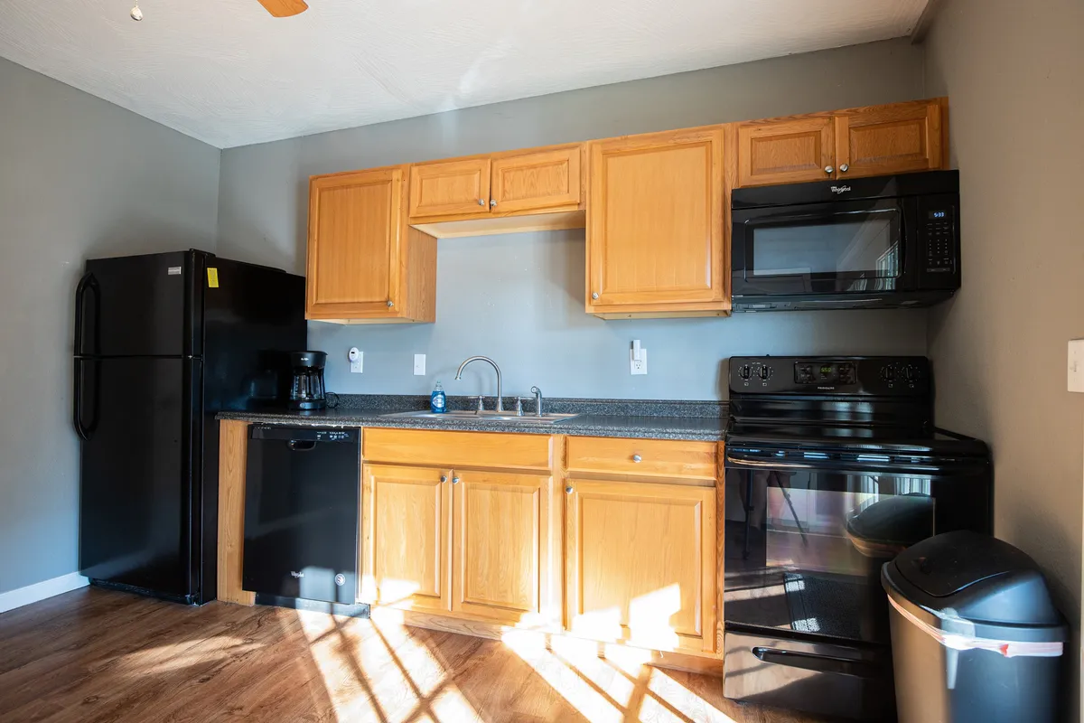 This image features a kitchen with ample cabinetry, sleek black appliances, and spacious countertops. The setup is functional and homey, suggesting a space where meal prep and cooking are both comfortable and enjoyable.