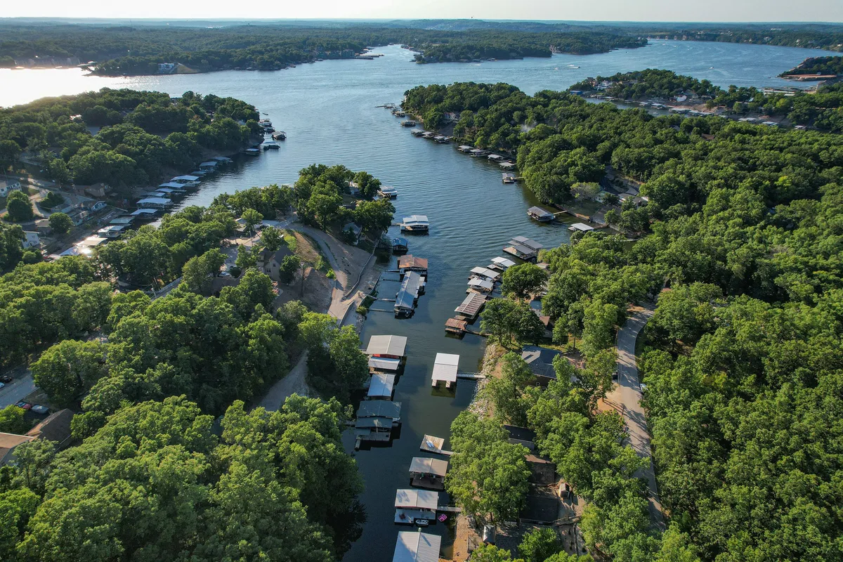 A tranquil view over the river with boathouses nestled among lush greenery. The calm water and surrounding landscape evoke a sense of peaceful escape, ideal for scenic cruises or quiet moments spent together.