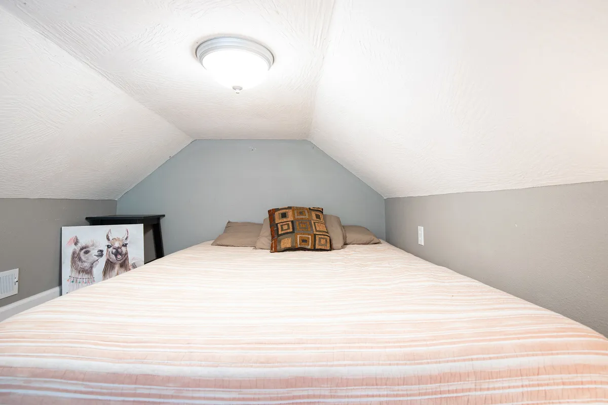 A welcoming bedroom scene featuring a comfortable bed, decorative pillows, animal-themed artwork, and a nightstand. Soft natural light filters through, enhancing the intimate and peaceful mood.