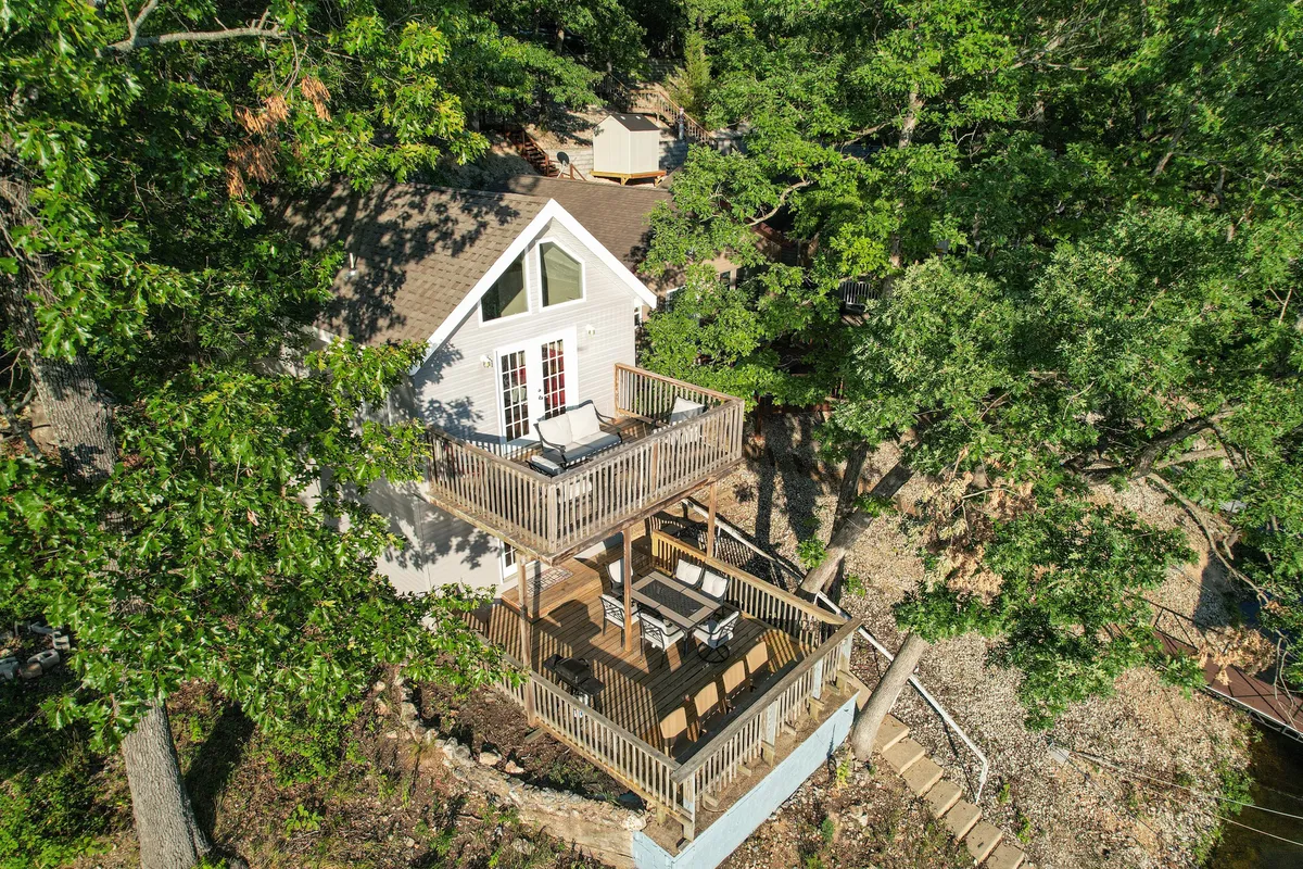 A serene two-level back deck surrounded by trees and offering a waterfront view. Outdoor seating invites relaxation or meals with nature as a backdrop, and the expanse of the deck suggests easy indoor-outdoor living.
